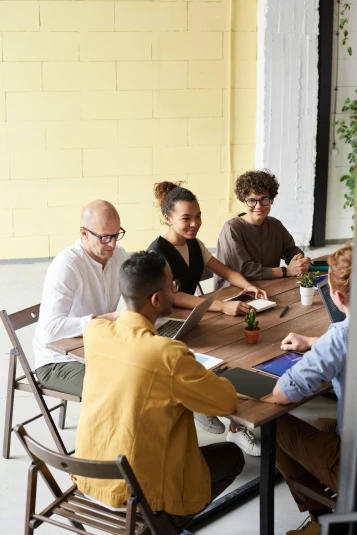 Five people sat around a table having a meeting